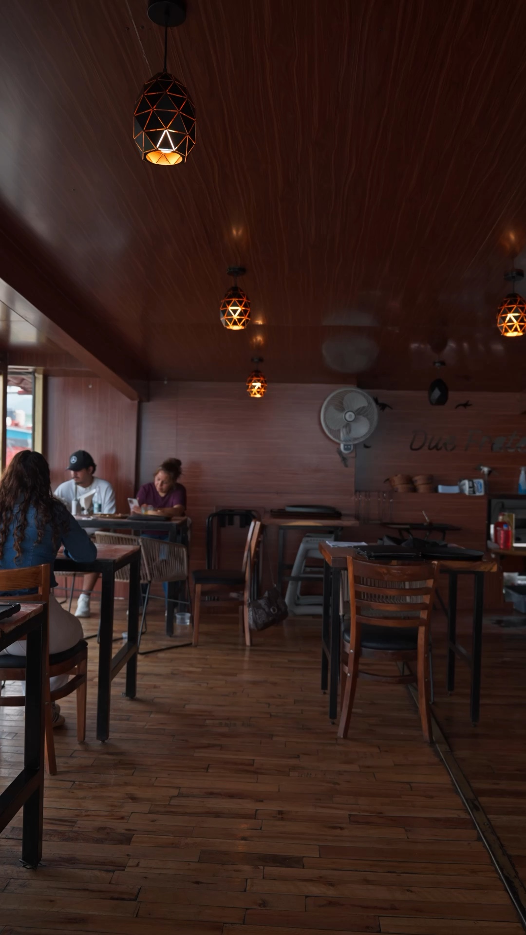 Comensales de Due Fratelli frente al ventanal del restaurante, fotograma de la pieza audiovisual gastronómica.